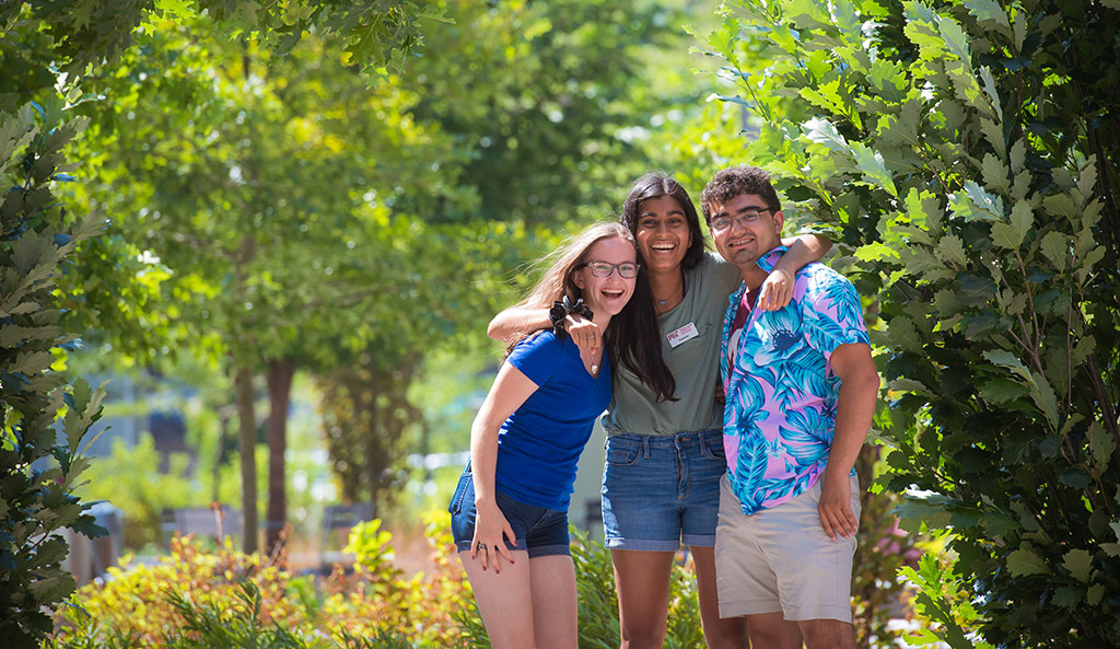 Three happy MIT tour guides outdoors on campus